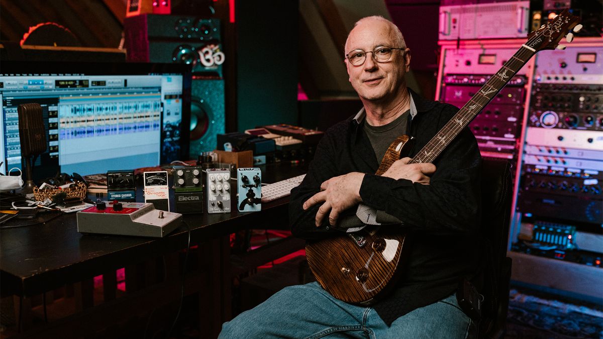 Paul Reed Smith holding Guitar next to table with pedals